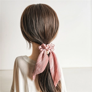 Pink pleated satin scrunchie with long ribbons and pearl charm on female ponytail
