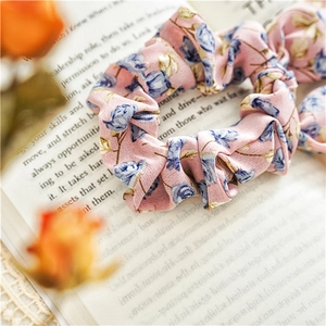 Close-up of pink floral scrunchie with blue rose prints on vintage book background