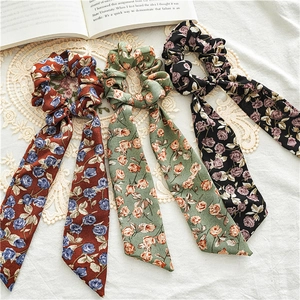 Detail shot of floral scrunchies with long ribbons on white fabric and vintage book