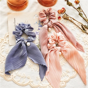 Detailed view of pleated satin scrunchies with long ribbons and pearl accents
