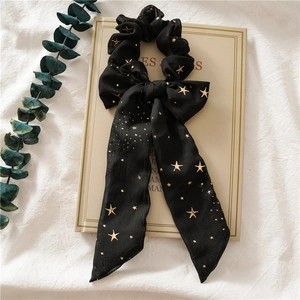 Detail eines schwarzen Chiffon-Haargummis mit Sternenmuster und langer Schleife