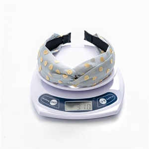 Light blue polka dot headband weighing 31.0g on a scale to show its lightweight feel