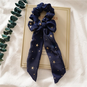 Detailansicht von marineblauem Chiffon-Haargummi mit langen Bändern und Goldsternen