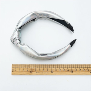 Silver knot headband with iridescent leather finish and non-slip lining on white background
