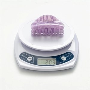 Detail shot of purple marble acrylic hair claw clip on scale weighing 20.9g