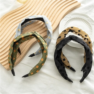 Detail view of four wide knot headbands in blue, green, khaki, and black with polka dots