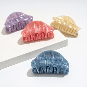 Detail view of oval acrylic hair claws showing marble ink patterns in four pastel colors
