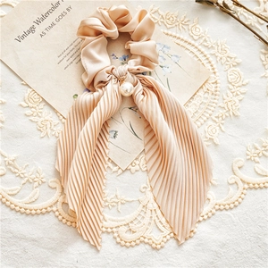 Detail of champagne satin hair scrunchie with pleated ribbon and white pearl ornament