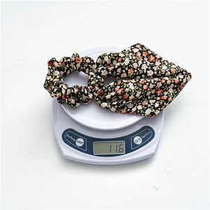 Close-up of a lightweight floral bow scrunchie on a scale weighing 11.6 grams
