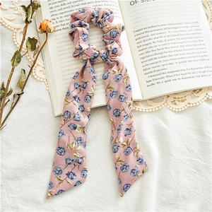 Detail of light pink floral scrunchie with blue rose patterns and long streamers on a book