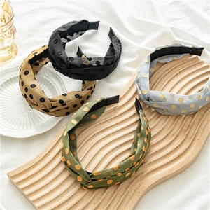 Detailed view of polka dot mesh knotted headbands in four colors on a wooden tray