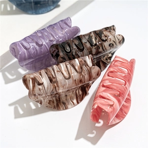 Detailed view of oval acrylic hair claws in assorted marbled patterns and colors