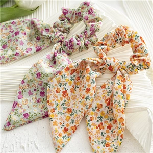 Detailed view of floral print scrunchies with long ribbons in green and yellow fabric