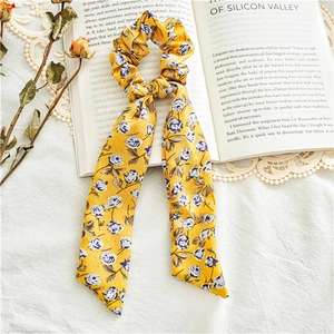 Detail of floral chiffon hair scrunchie with long ribbons on a vintage book backdrop