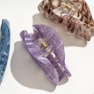 Detail view of large marble acrylic hair claws in purple, blue and brown tones