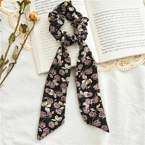 Detail of floral chiffon hair scrunchie with purple roses on a vintage book