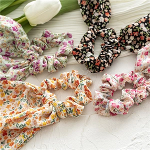 Floral print hair scrunchies in pastel colors displayed on white textured stone background