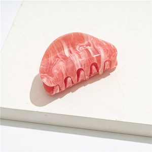 Detail shot of a pink marble acrylic hair claw clip with a glossy translucent finish
