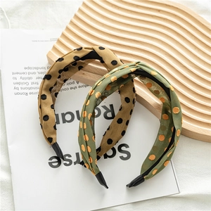Detail of twisted polka dot headbands in mustard and olive green on wooden tray