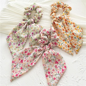 Detailed shot of three floral scrunchies with long ribbons in green yellow and pink colors