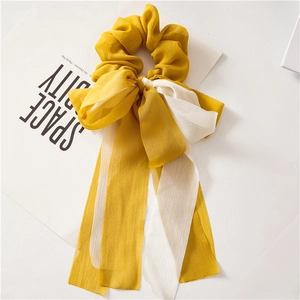 Détail d'un chouchou en mousseline jaune et blanc avec de longs rubans élégants