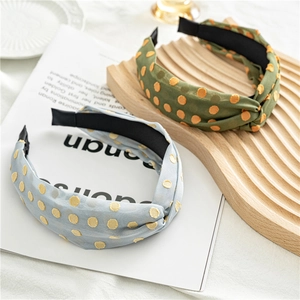 Detail of two wide knotted headbands with dot embroidery on a wooden tray