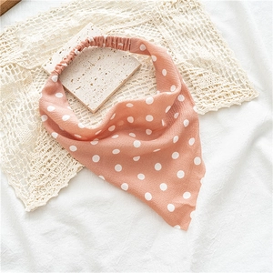 Détail du bandeau élastique rose à pois posé sur un support en marbre et dentelle