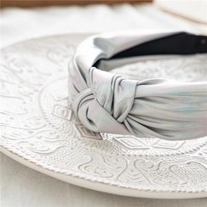 Macro shot of silver holographic knotted headband with metallic finish and black non-slip lining