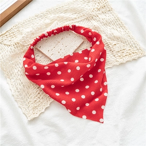 Détail d'un bandeau triangle rouge à pois avec bande élastique sur un fond en dentelle