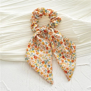 Detail of floral chiffon hair scrunchie with long ribbons in cream and orange