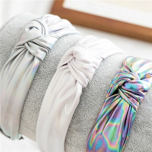 Detailed view of wide knotted headbands in holographic silver, white, and iridescent fabrics