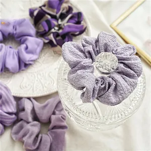 Détail de chouchous violets en tissus côtelés, floraux et seersucker sur plat en céramique