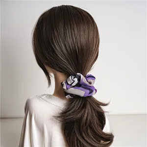 Détail d'un chouchou en satin à motif géométrique violet sur une queue de cheval brune