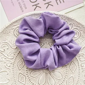 Détail d'un chouchou côtelé violet clair sur une assiette décorative en céramique blanche