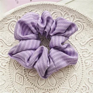 Détail d'un chouchou en mousseline à rayures violettes sur une assiette blanche à relief