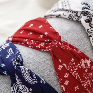 Détail macro de trois bandeaux à nœuds paisley en rouge, bleu marine et tissu blanc