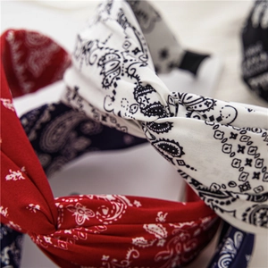 Détail rapproché de serre-têtes larges à motif paisley avec nœud croisé tendance