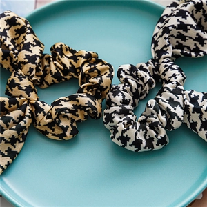 Detail of satin houndstooth scrunchies with bow tie in a blue ceramic dish