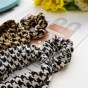 Detail of satin houndstooth scrunchies with long ribbons in black, white, and yellow