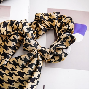 Detailed shot of houndstooth silk satin scrunchie with a bow and long streamer