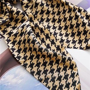 Detail shot of houndstooth satin fabric scrunchie with elegant silk-like texture and sheen