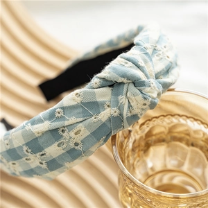 Détail d'un serre-tête à carreaux bleu clair avec broderie florale blanche et nœud rétro