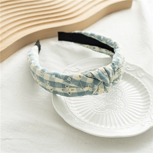 Détail du serre-tête vichy bleu clair avec broderie florale blanche et nœud supérieur