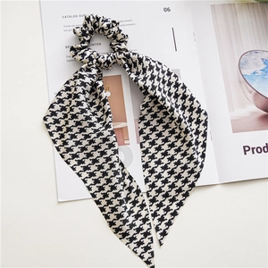 Detail of elegant black and white houndstooth hair scrunchie with long ribbon streamers