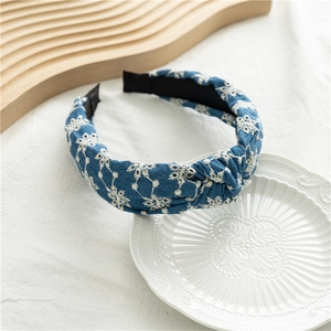 Détail du serre-tête noué en denim bleu avec de délicates broderies florales blanches