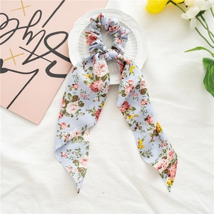 Détail du chouchou à fleurs avec longs rubans en tissu bleu clair et motif de roses