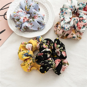 Gros plan de chouchous à fleurs vintage en bleu pastel, noir, jaune et rose tendre