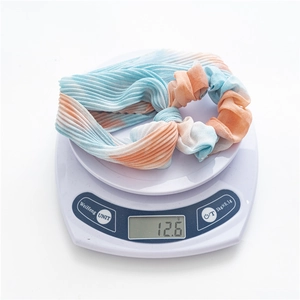 Détail d'un chouchou plissé tie-dye pesant 12,6 g sur une balance numérique de précision