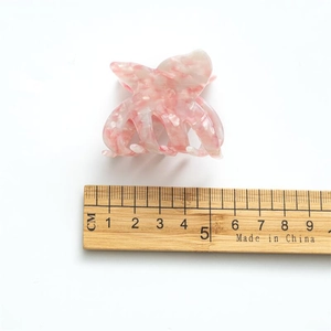 Pince à cheveux papillon en acétate rose marbré, taille 5,5 cm sur fond blanc