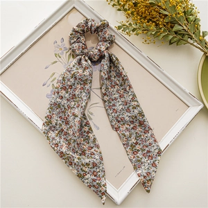 Détail d'un chouchou en mousseline florale avec longs rubans sur cadre vintage